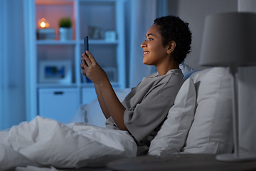 Image showing african woman with smartphone in bed at night