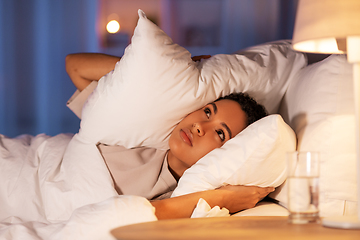 Image showing angry african woman lying in bed and closing ears