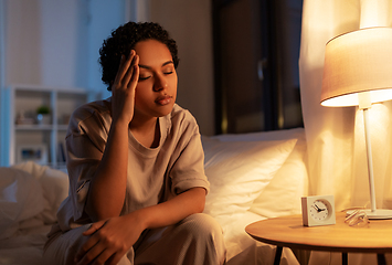 Image showing stressed african woman lying in bed at night