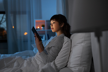 Image showing asian woman with tablet pc in bed at home at night