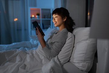 Image showing asian woman with tablet pc in bed at home at night