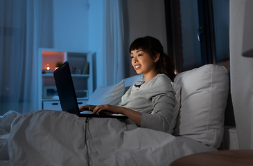 Image showing woman with laptop in bed at home at night