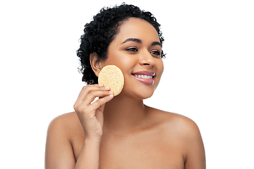 Image showing young woman cleaning face with exfoliating sponge