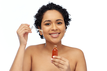 Image showing happy african american woman with bottle of serum