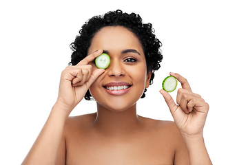 Image showing happy african woman making eye mask of cucumbers