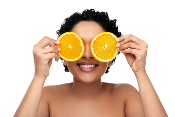 Image showing smiling african woman making eye mask of oranges