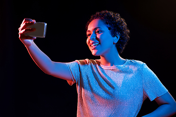 Image showing woman taking selfie with smartphone in neon lights