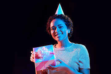 Image showing african woman in party cap with gift box on black