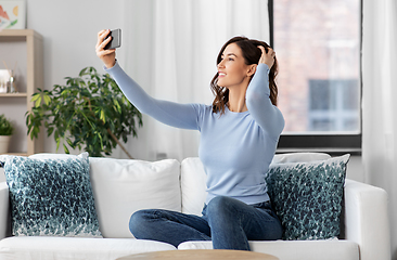 Image showing happy woman with smartphone taking selfie at home