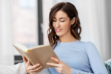 Image showing young woman reading book at home