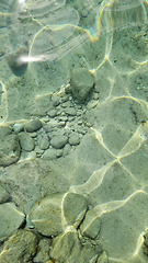 Image showing Blurred abstract marine background, stones underwater. Clear sea water covers the rocks