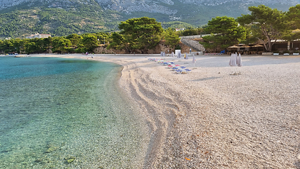 Image showing Beautiful shore of the Adriatic Sea. Bay view with beach and deck chairs. Sunrise