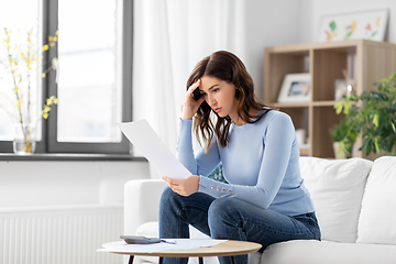 Image showing stressed woman with papers and calculator at home