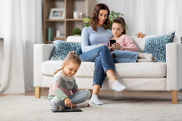 Image showing happy mother and daughters with smartphone at home