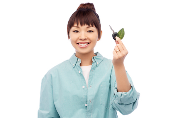 Image showing happy asian woman holding car key with green leaf