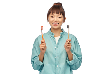 Image showing asian woman with wooden and plastic toothbrushes