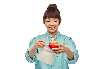 Image showing happy woman putting apple into reusable bag