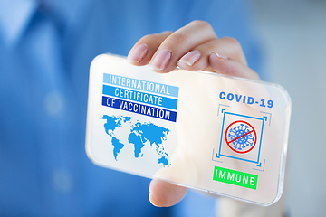 Image showing hand with certificate of vaccination on smartphone