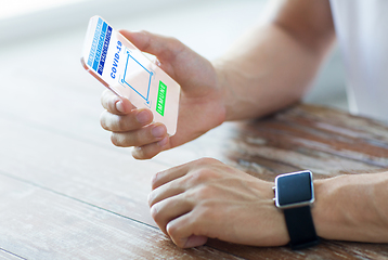 Image showing hand with certificate of vaccination on smartphone