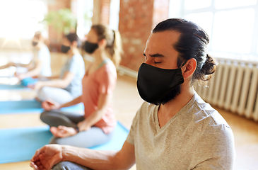 Image showing group of people in masks doing yoga at studio