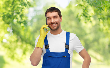 Image showing happy male worker or cleaner calling on smartphone