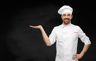 Image showing happy smiling male chef holding something on hand