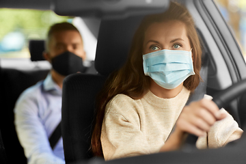 Image showing female driver in mask driving car with passenger