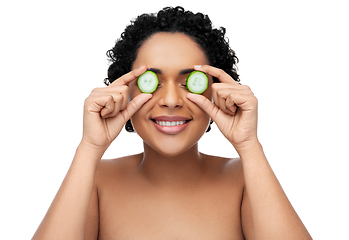 Image showing happy african woman making eye mask of cucumbers