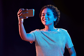 Image showing woman taking selfie with smartphone in neon lights