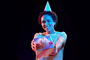 Image showing african woman in party cap with gift box on black