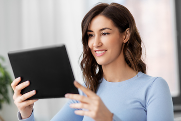 Image showing happy smiling young woman with tablet pc at home