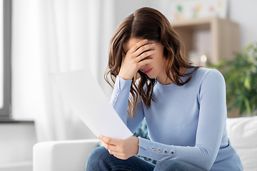 Image showing stressed woman with paper sheet at home