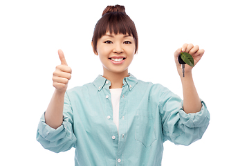 Image showing happy asian woman holding car key with green leaf