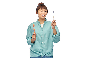 Image showing asian woman with wooden and plastic toothbrushes