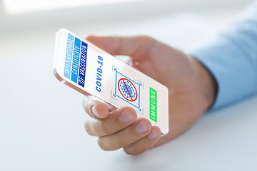 Image showing hand with certificate of vaccination on smartphone