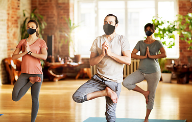 Image showing group of people in masks doing yoga at studio