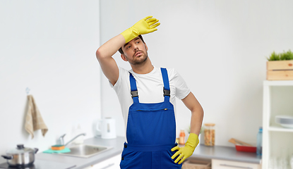 Image showing tired male worker or cleaner in gloves at kitchen