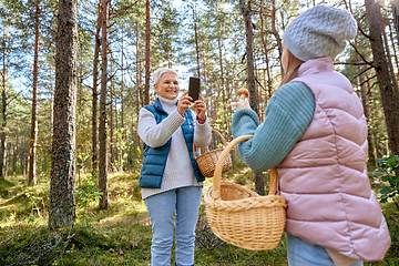 Image showing grandma photographing granddaughter with mushrooms