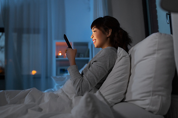 Image showing asian woman with smartphone in bed at night