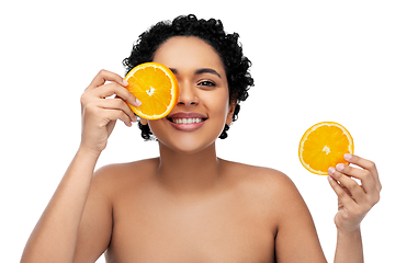 Image showing smiling african woman making eye mask of oranges