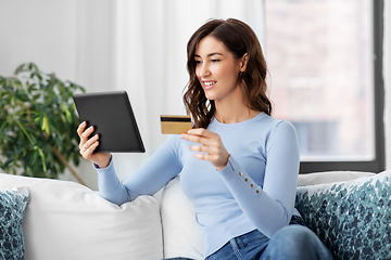 Image showing happy woman with tablet pc and credit card at home