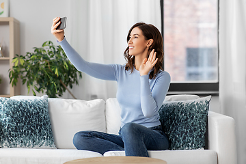 Image showing happy woman with smartphone taking selfie at home