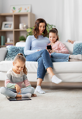 Image showing happy mother and daughters with smartphone at home