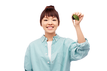 Image showing happy asian woman holding car key with green leaf