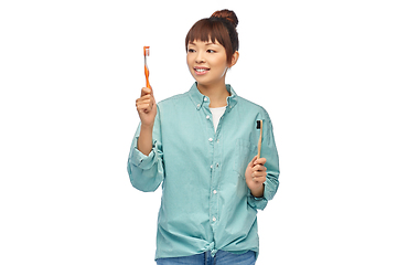 Image showing asian woman with wooden and plastic toothbrushes