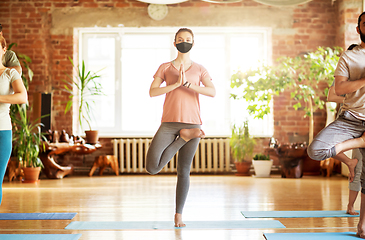 Image showing group of people in masks doing yoga at studio