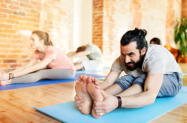 Image showing group of people doing yoga forward bend at studio