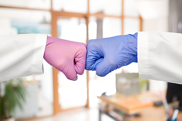 Image showing hands of doctors in gloves make fist bump gesture