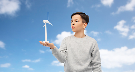 Image showing boy with toy wind turbine over blue sky and clouds