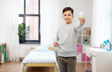 Image showing happy boy comparing different light bulbs at home